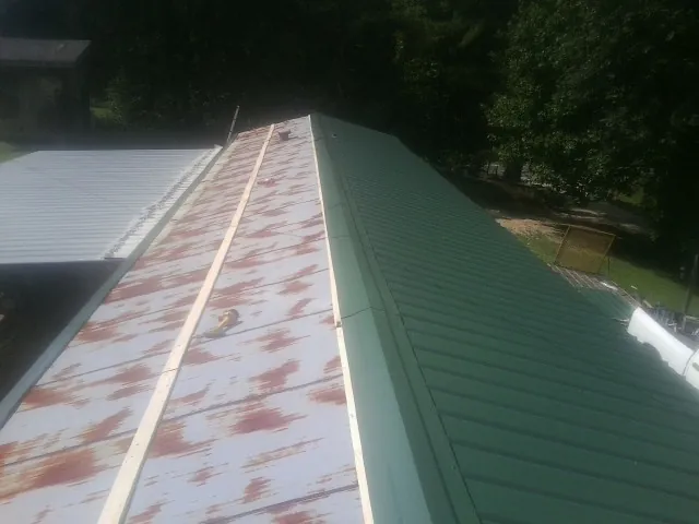 Old rusted panels beside newly installed green metal roofing — Wind Damage Roof Repair by Roofing Brothers in Clarion
