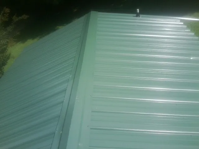 New green metal panels meeting at the ridge of a roof — Flat Roof Repair work by our crew in Clarion