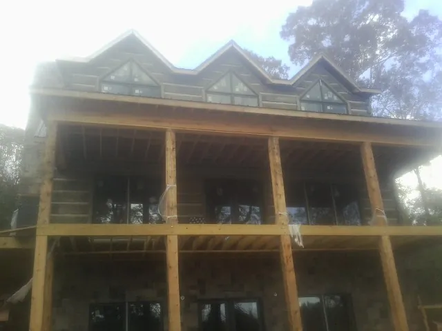 Dormers and porch framing on a large log home under construction — Roof Coating work by our crew in Clarion