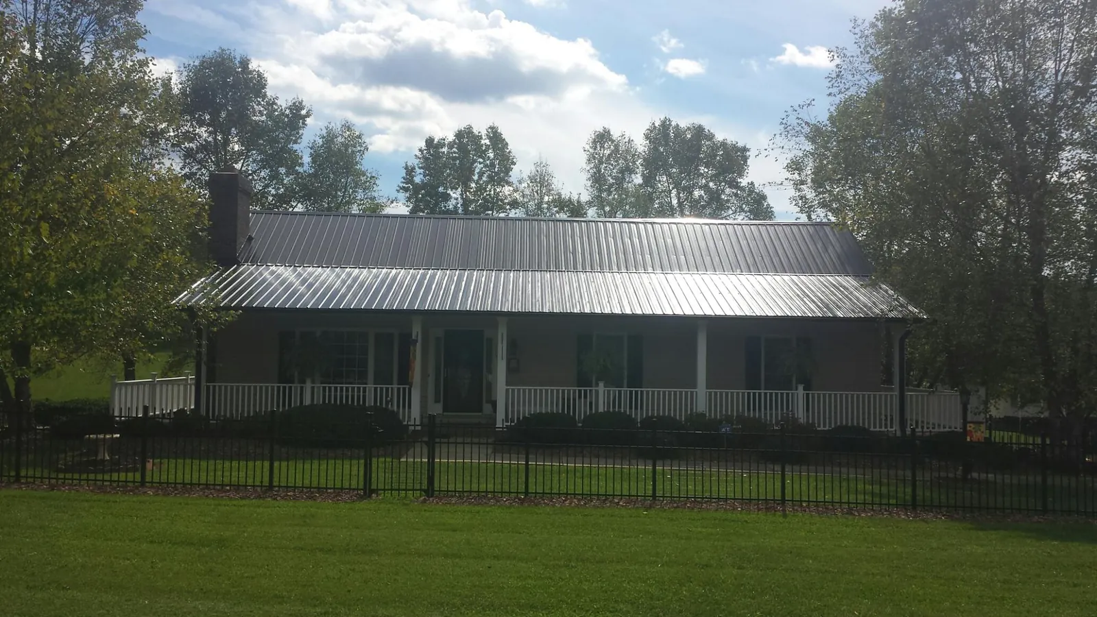 Gray metal roof on a brick ranch with a full width front porch — Gutter Guard Installation work by our crew in Clarion