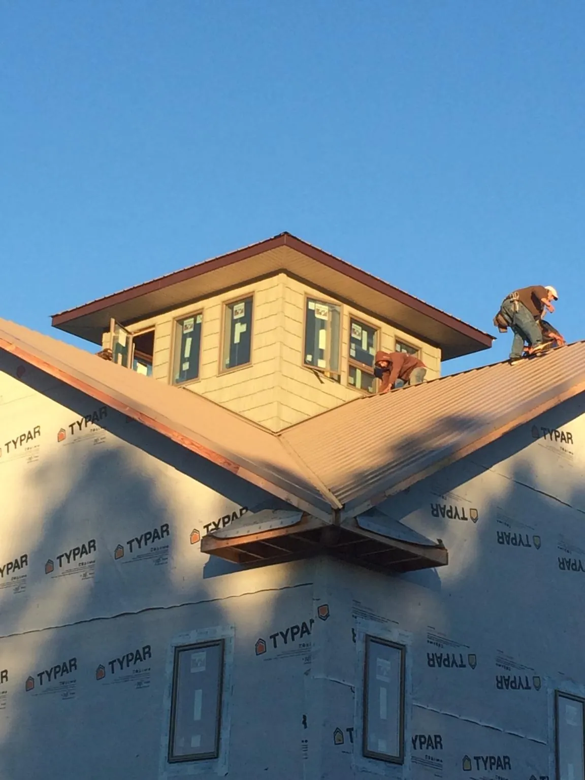 Roofers working around a rooftop cupola on a new metal roof at sunset — Roof Waterproofing in Clarion by Roofing Brothers